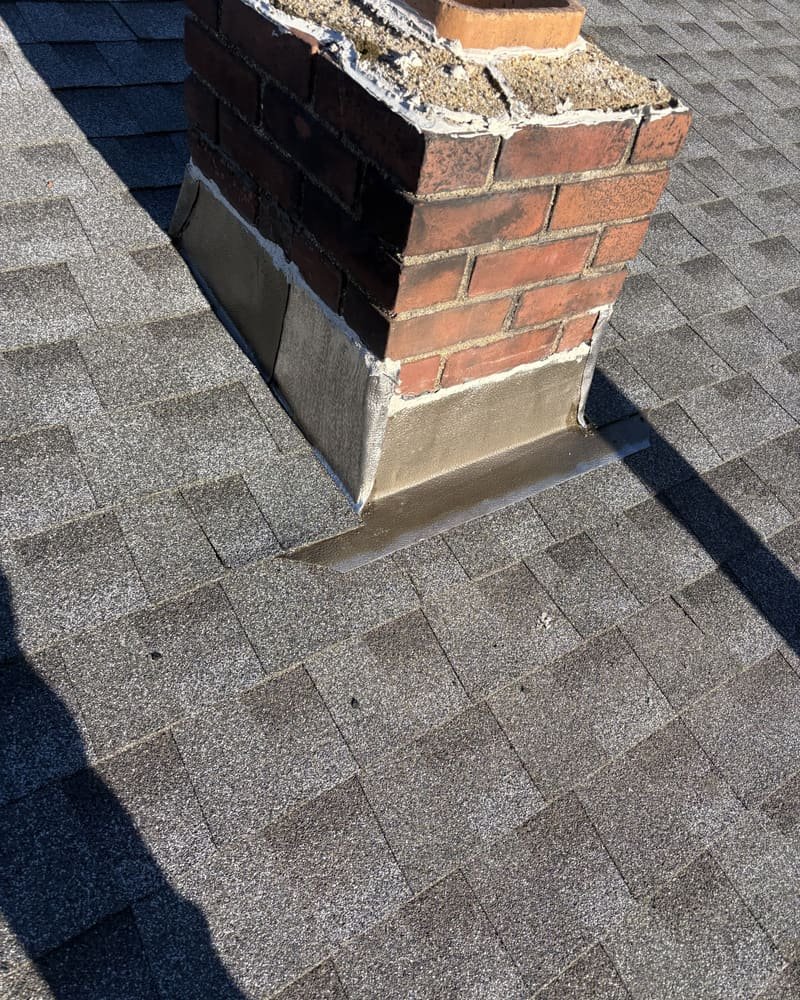Close-up of chimney step flashing and shingle work on a residential roof in Southern NH