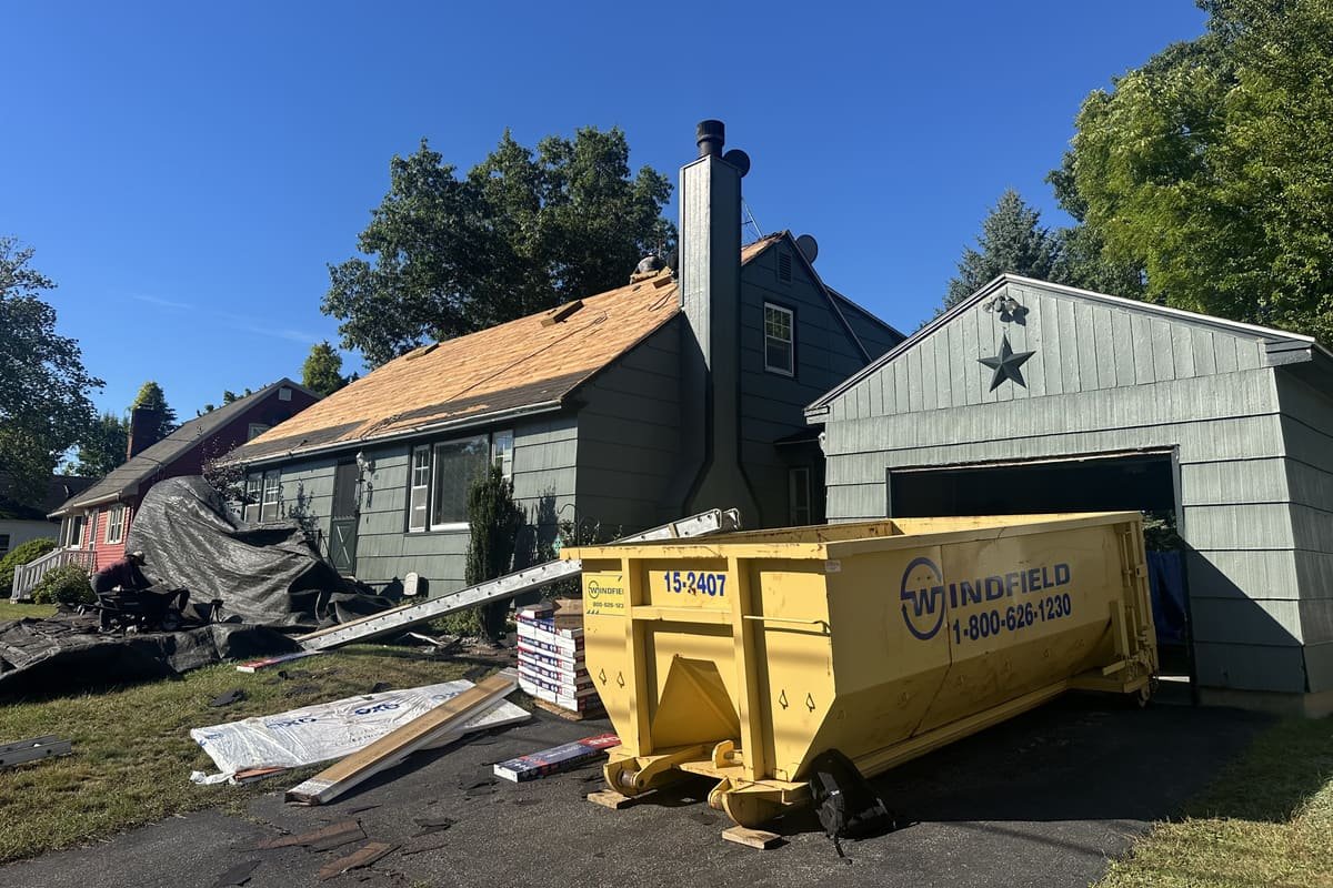 Storm damage roof restoration in progress showing exposed decking and shingle bundles ready for installation